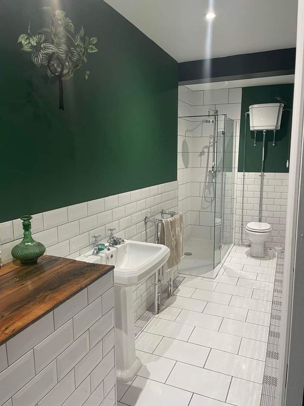 Traditional bathroom with metro tiles, a high-level cistern and a timber vanity top.