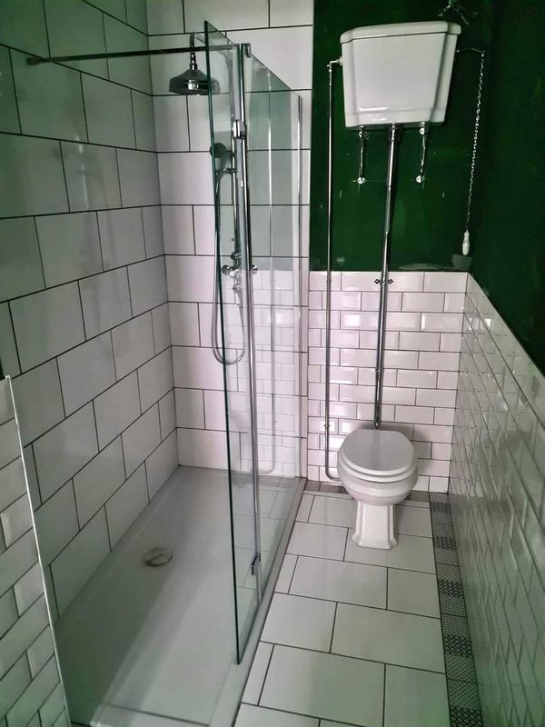 The same bathroom: walk-in shower beside the high-level cistern toilet.