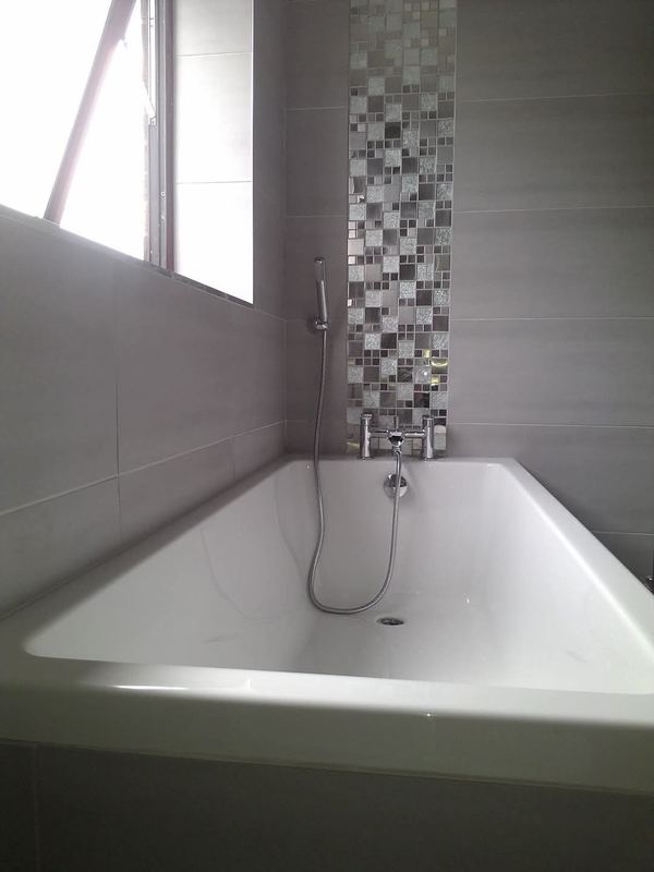 Bath with a mosaic feature strip and a shower mixer.