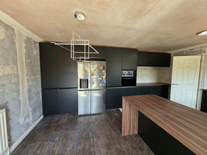 The same kitchen, with a walnut-effect island and tall larder units.