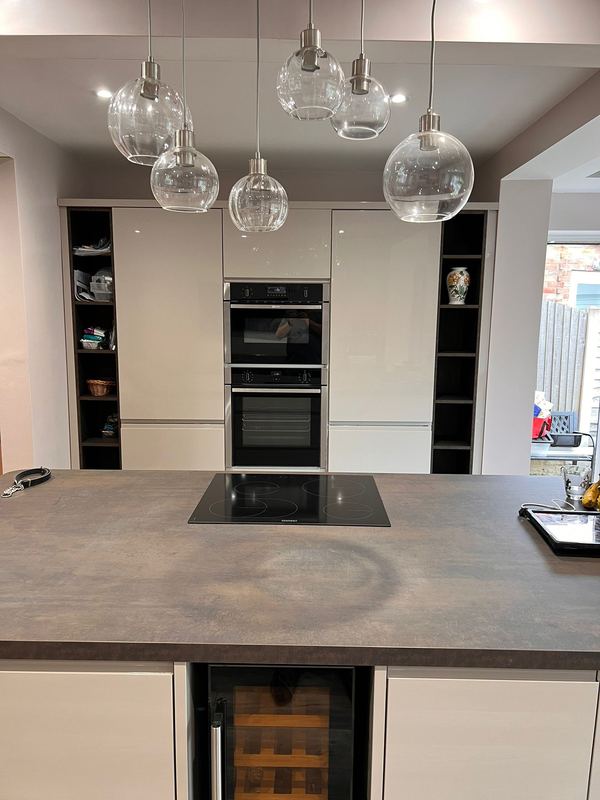 Handleless kitchen with an island, induction hob and glass pendant lights