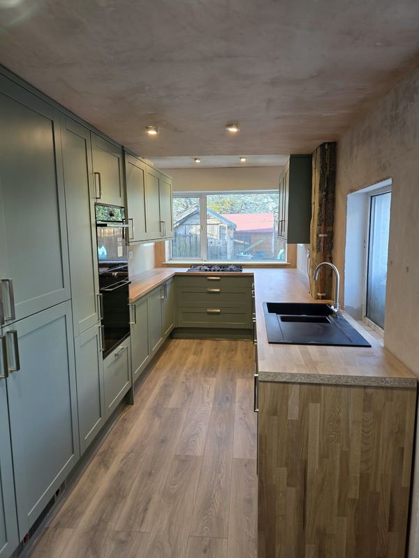 Sage Shaker kitchen with oak worktops and integrated ovens.