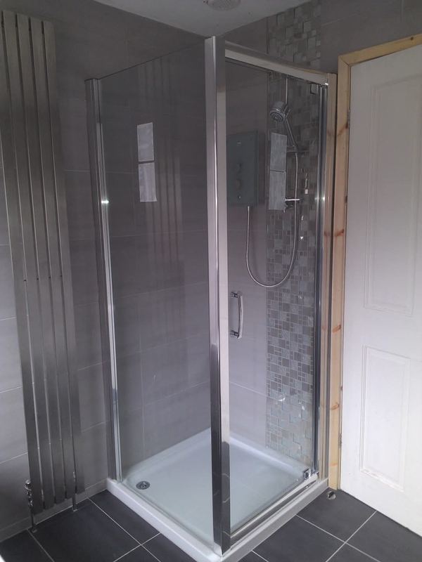 Corner shower enclosure with grey tiles and a mosaic feature strip.