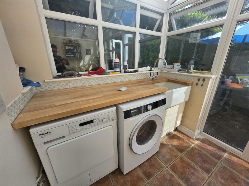 Utility room with oak worktops, a Belfast sink and space for the washer and dryer.