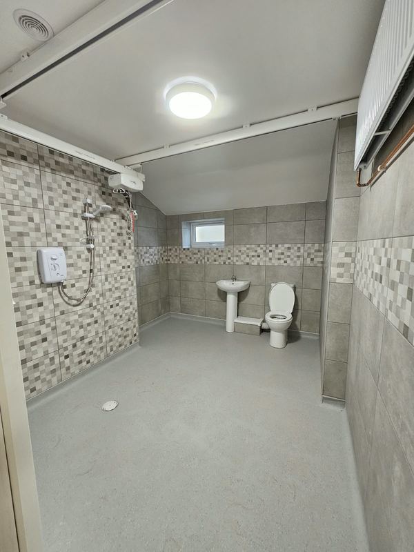 Accessible wetroom with a level floor throughout, a floor drain and a ceiling track hoist